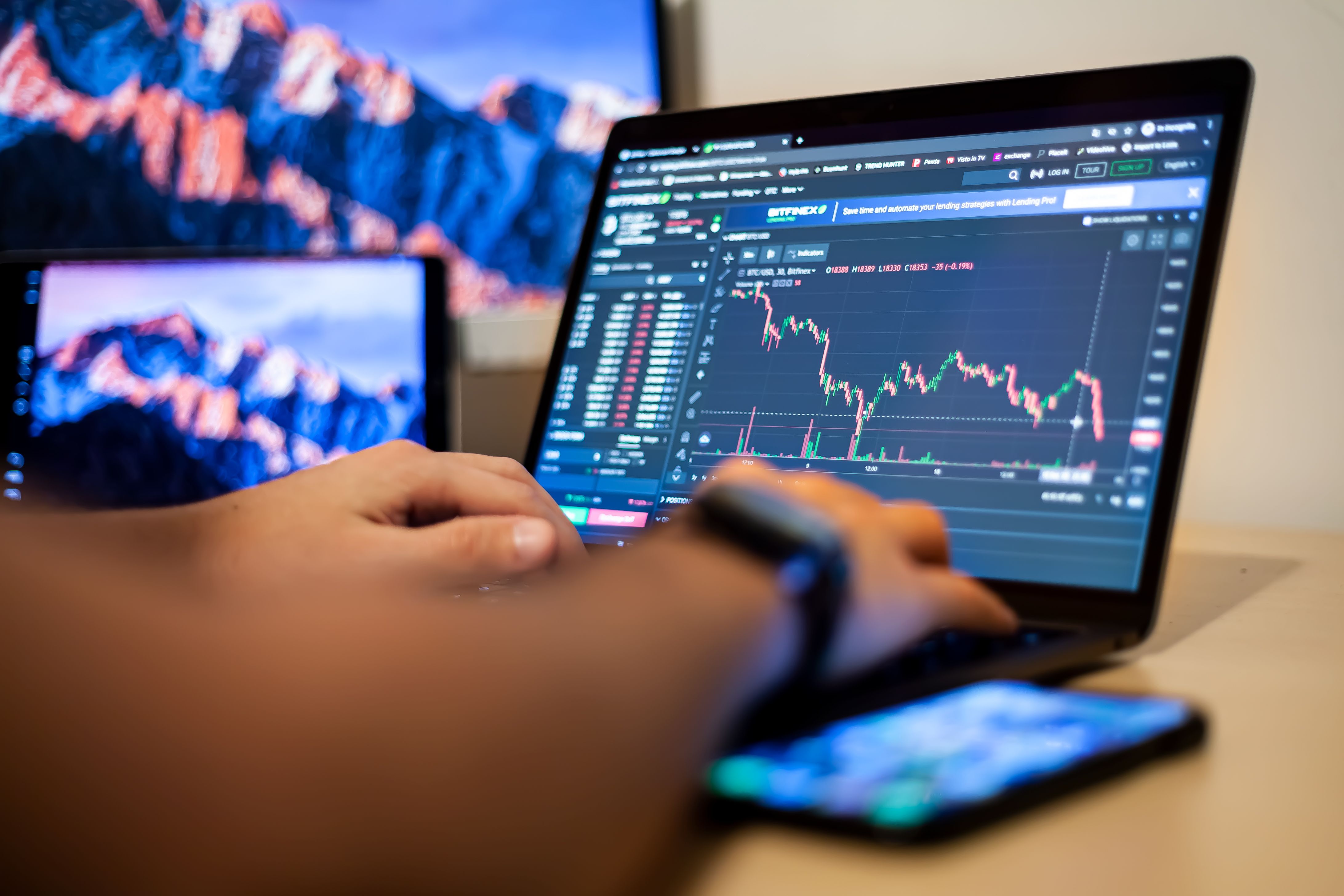Hands using a laptop with financial charts for an online forex trading session.