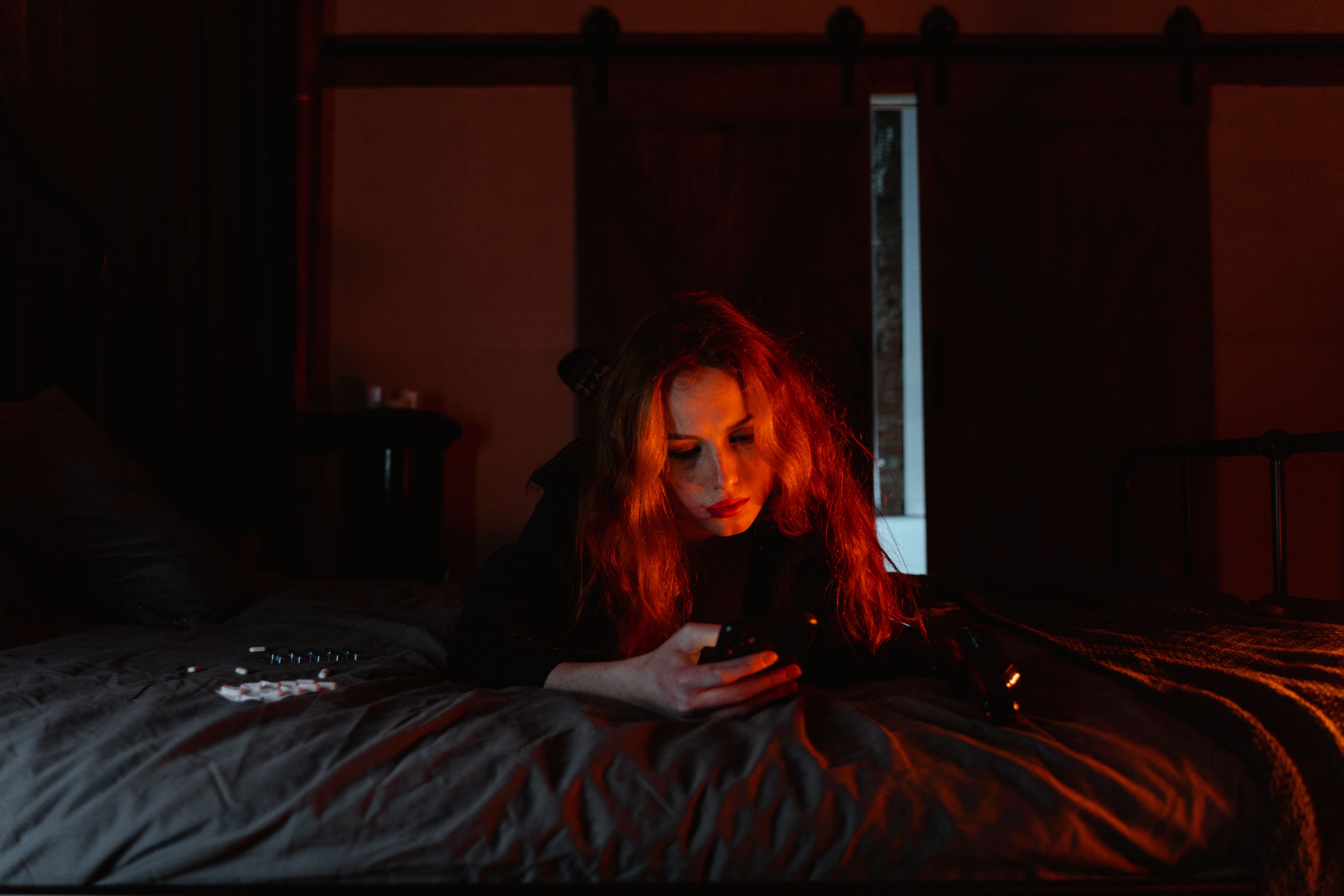 Woman using her phone alone in bed at night, suggesting the private and emotional side of digital connection.