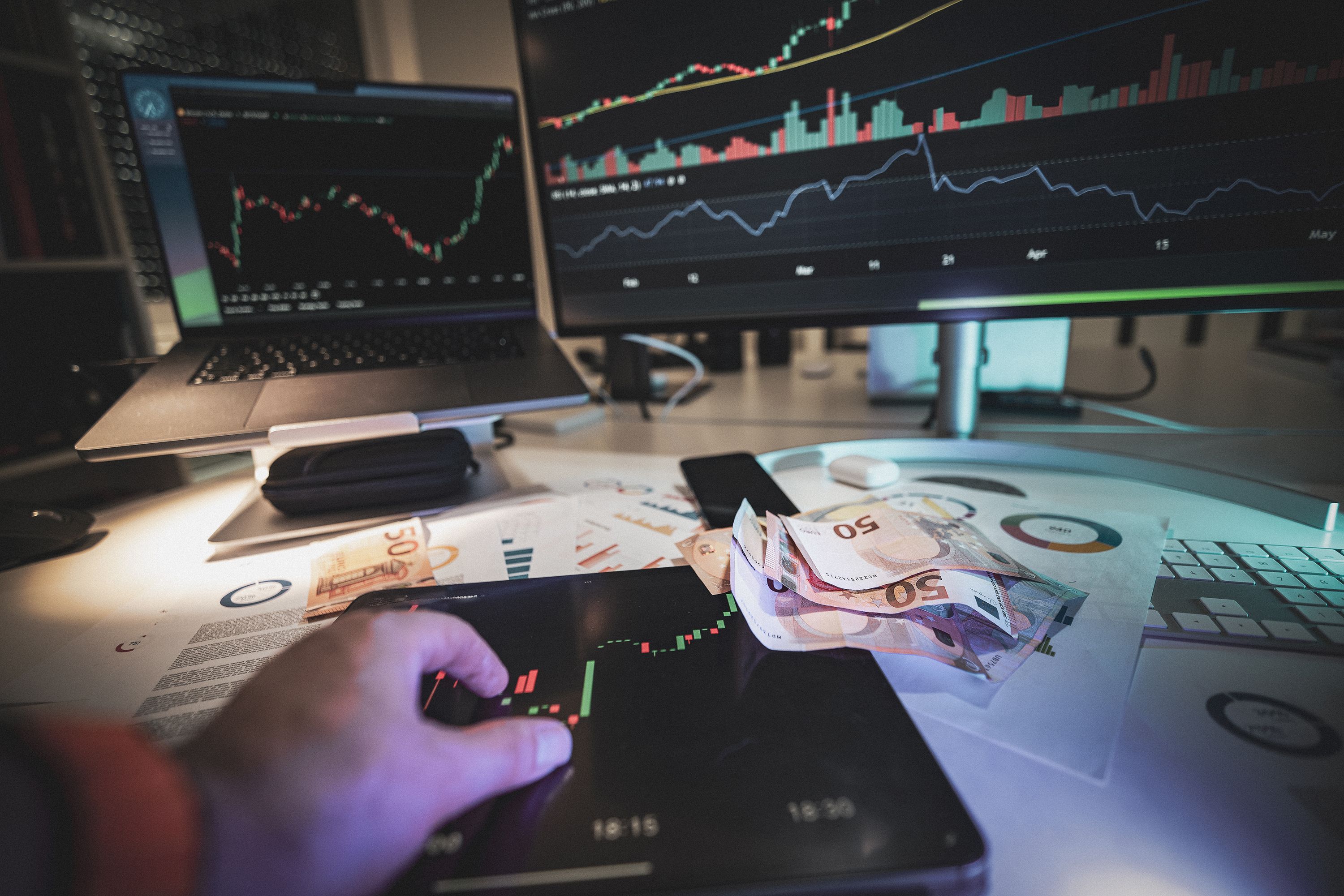 Trading desk with financial charts on screens and euro banknotes, illustrating currency-market analysis.